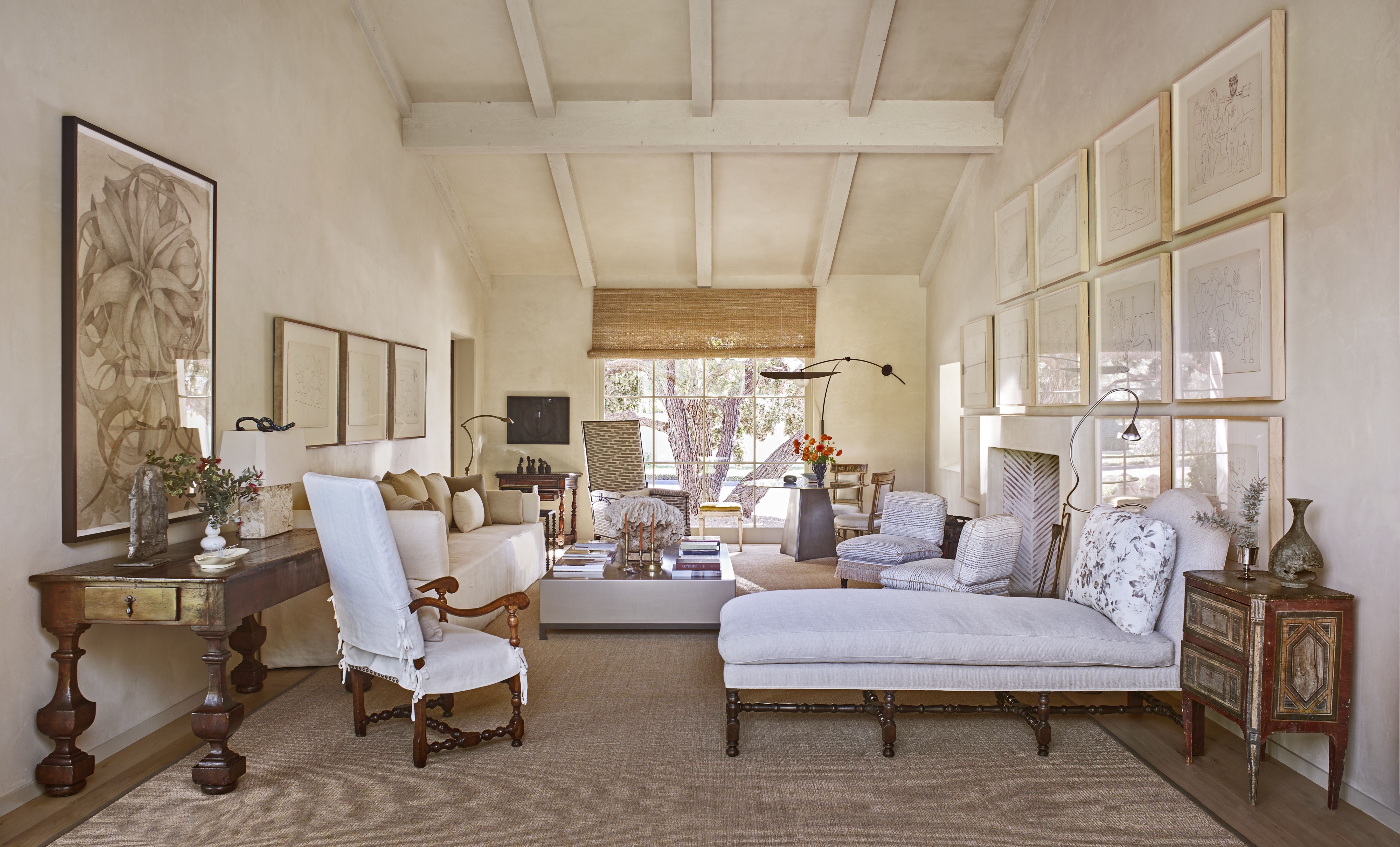 Designer living room with an off-white chaise lounge and matching furniture, a beamed ceiling and sunlight streaming in though floor to ceiling windows